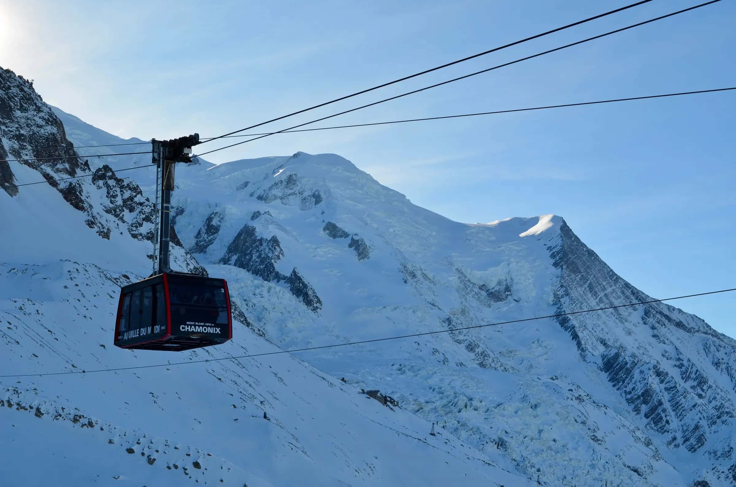 Cable car ascending Aiguille du Midi with Mont Blanc as a backdrop in winter, Chamonix.