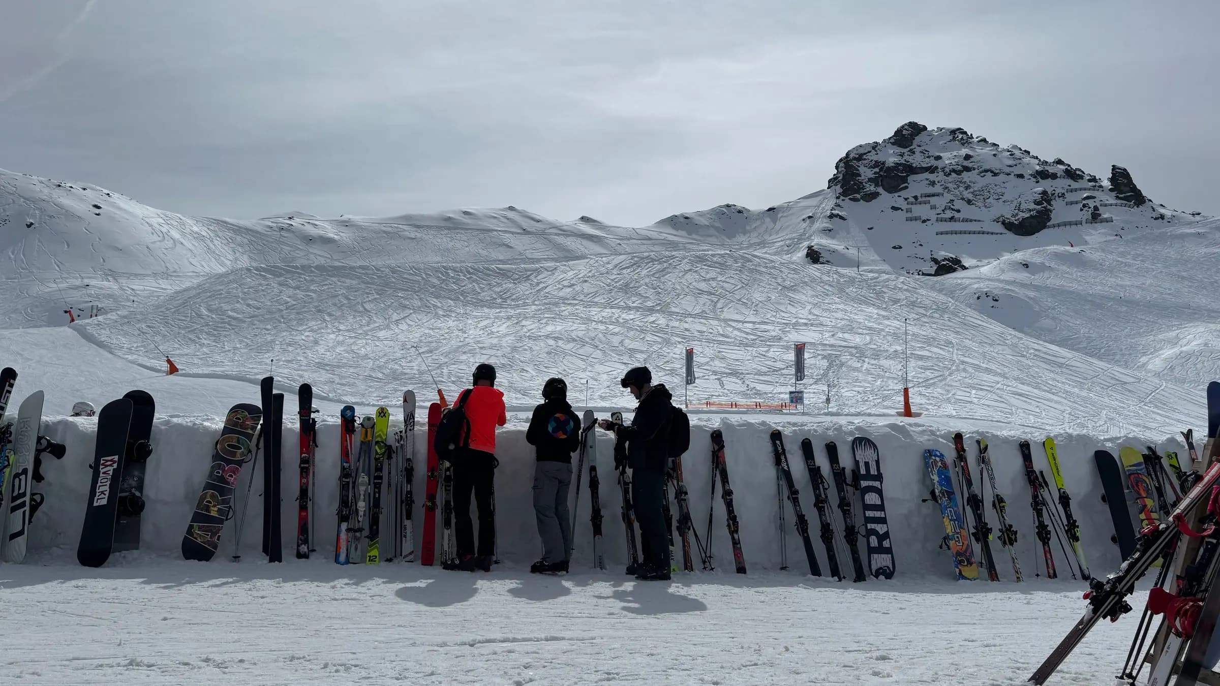 Skiers enjoying a bright day at an Alpine ski resort, surrounded by snow and skiing gear.