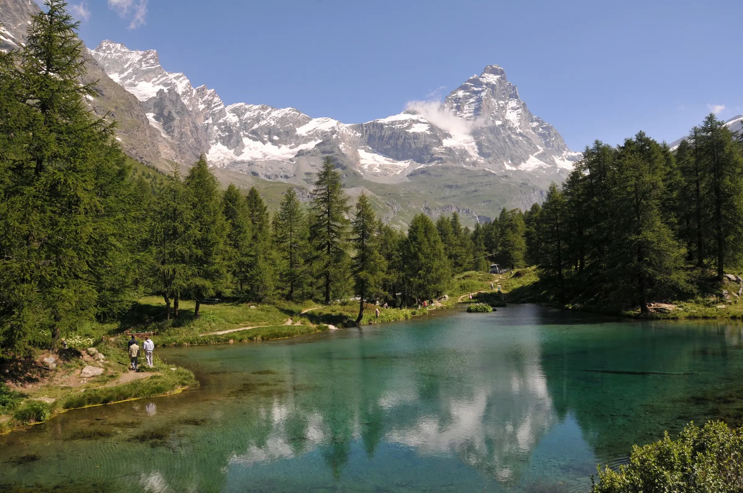 Stunning view of the Matterhorn reflected in a tranquil lake surrounded by lush trees in Valle d'Aosta, Italy.