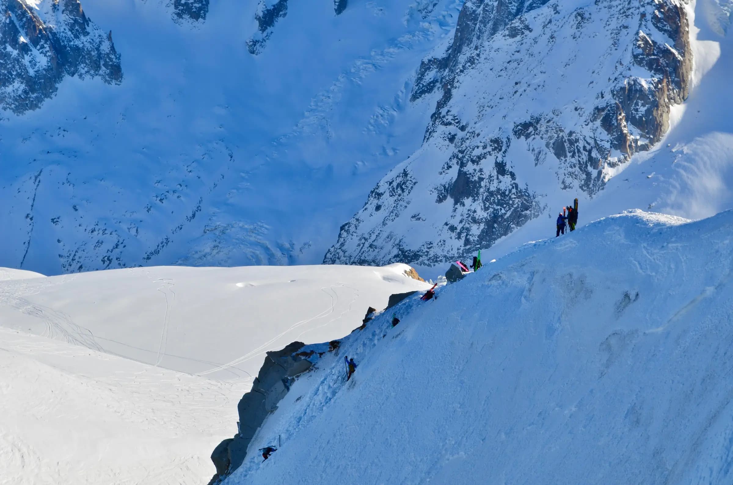 Dramatic winter view of Chamonix-Mont-Blanc with snow-covered peaks and climbers.