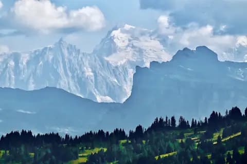 I took this photo during summer from the ski lift at Secteur Mont Chéry ski resort (elevation approximately 1700m), above the village of Les Gets. The intermediate black mountain with the precipice is Tête à l'Âne of 2800m elevation. In the background, the jagged rocky peak on the left is Aiguille du Midi (about 3850m), while the big snowy mountain is Mont Blanc du Tacul (about 4250m high). The main peak of Mont Blanc is off to the right, shrouded in cloud.