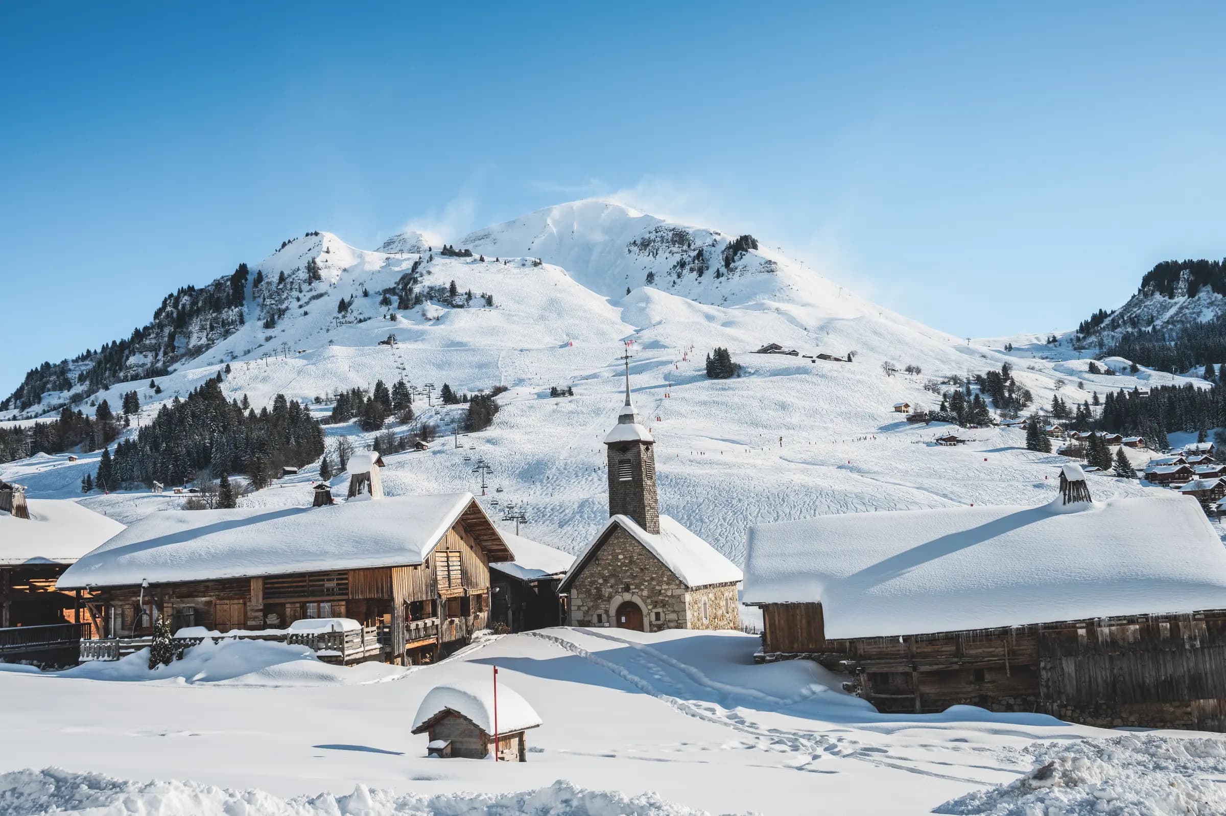 Charming village nestled in snowy mountains under a clear blue sky. Perfect winter scene.