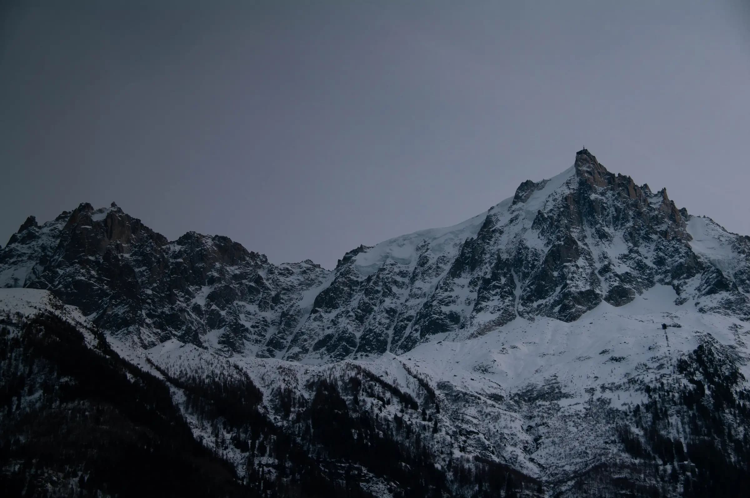 Snow-covered peaks of Chamonix-Mont-Blanc under an overcast sky, capturing the serenity of winter in the French Alps.