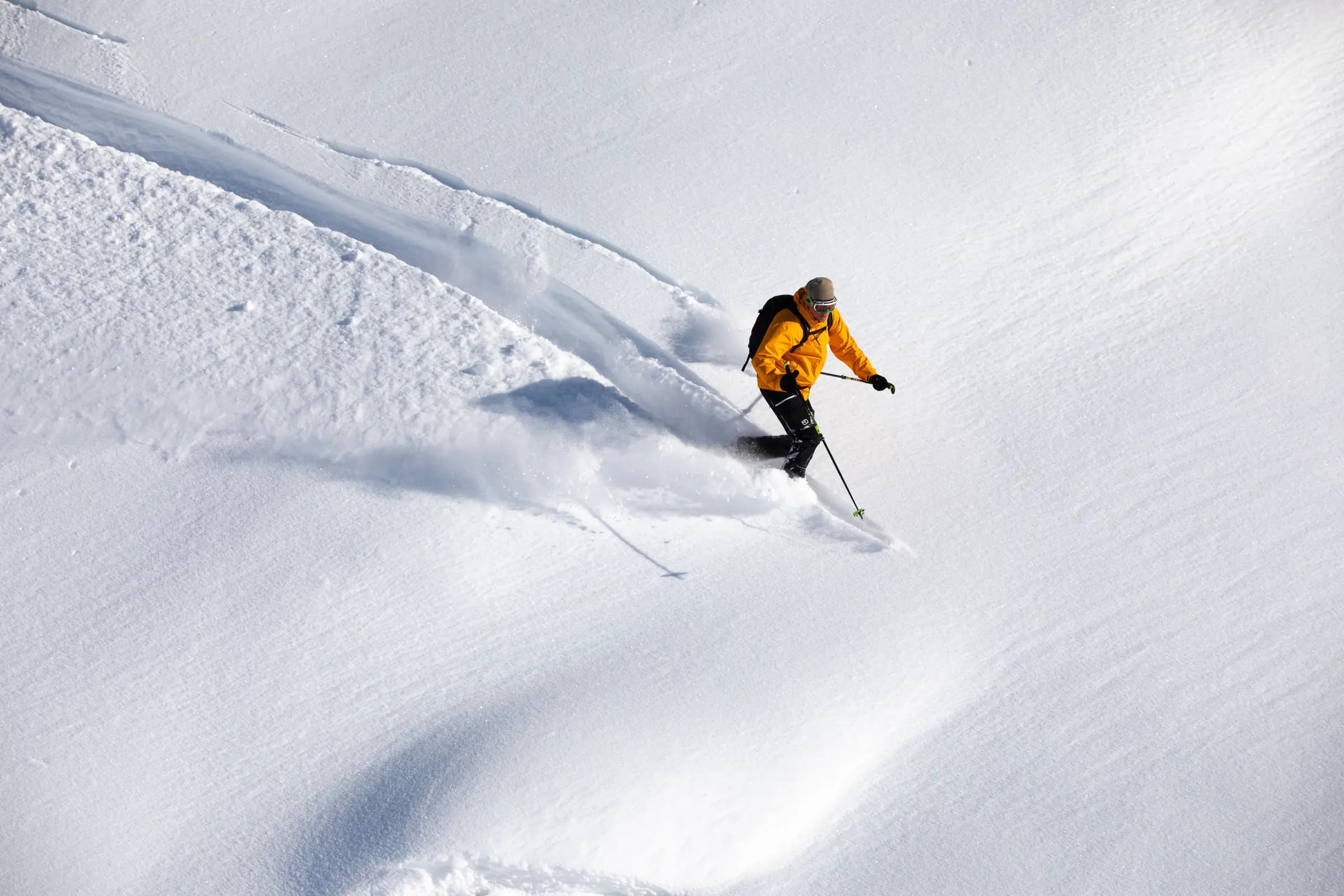 A skier in a yellow jacket expertly descends a snowy slope, showcasing winter sports adventure.
