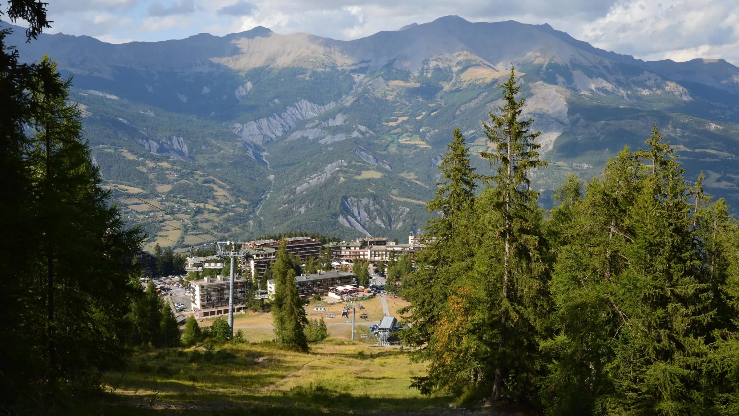 A scenic view of a mountain resort surrounded by lush green trees and expansive peaks.
