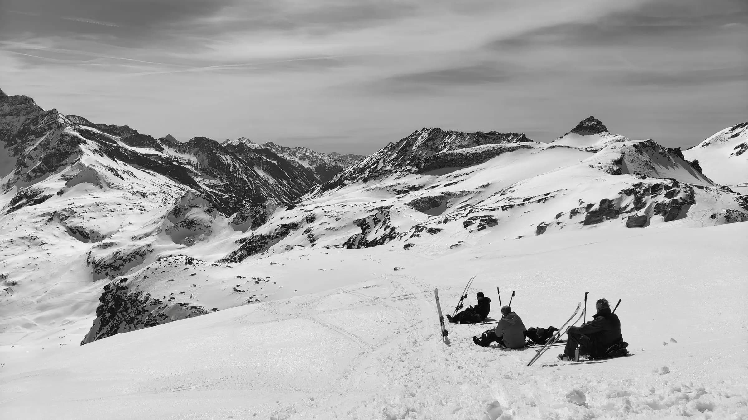 Skiers take a break on a snowy slope in the Austrian Alps with scenic mountain views.