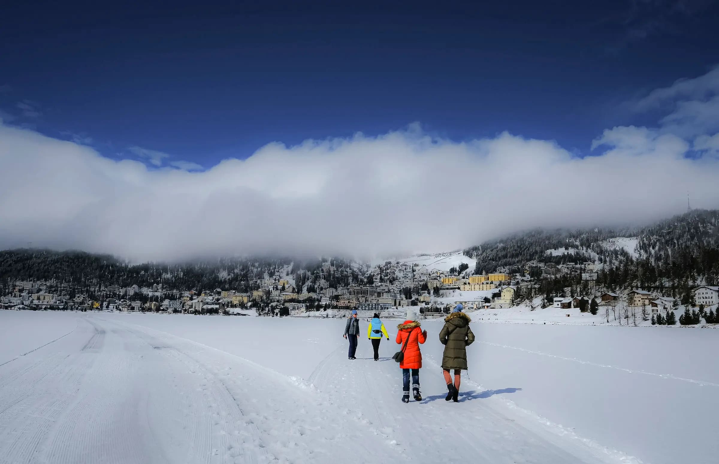 People enjoying a winter walk in snowy St. Moritz, Switzerland.