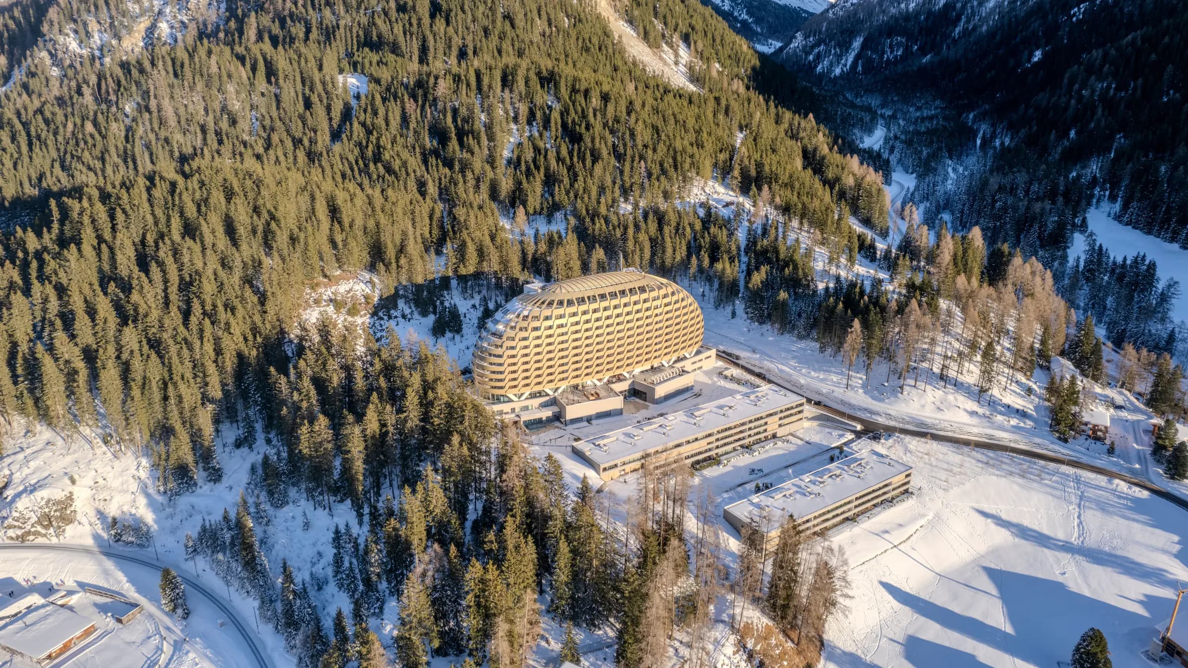 Stunning aerial view of a modern hotel surrounded by snowy forests in the Swiss Alps, Davos.