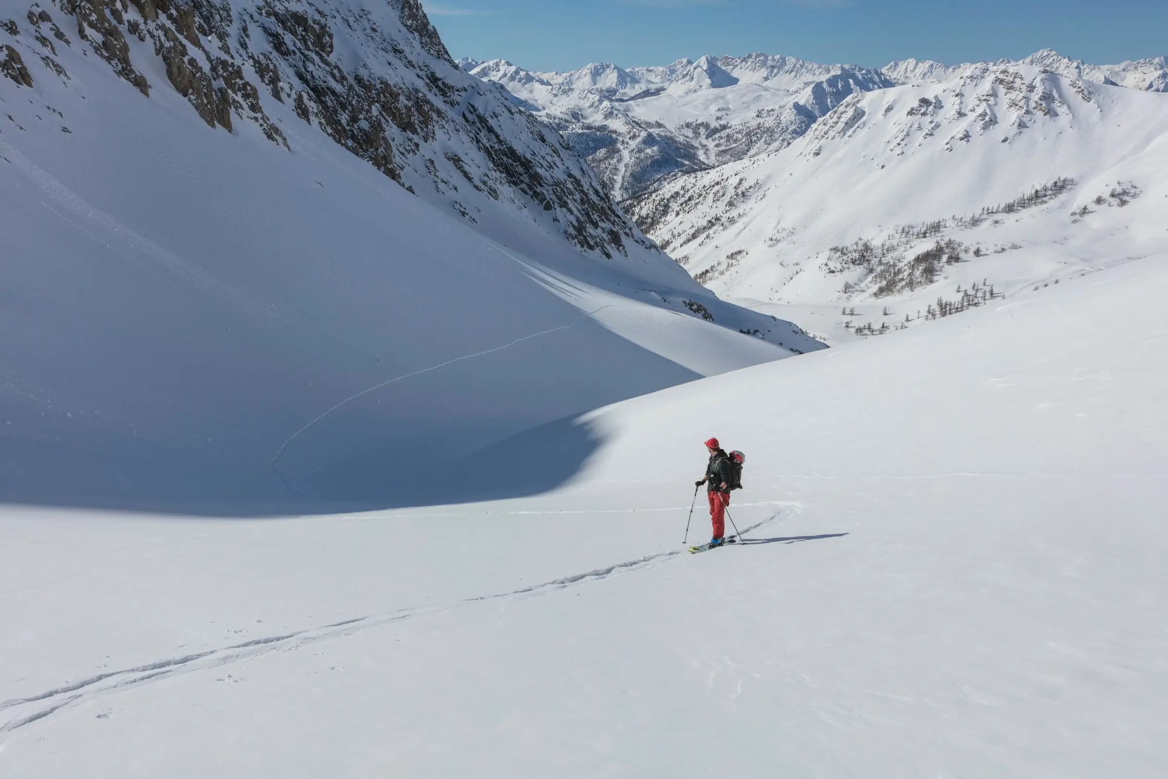 person in red jacket and blue pants standing on snow covered mountain during daytime