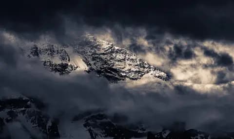 500px provided description: Distant snowy peaks glimpsed from Wengen, Switzerland early in a summer morning. Dark clouds moved in and out, partly obscuring the peak and the long glacier sliding down its side. [#sky ,#landscape ,#switzerland ,#nature ,#light ,#snow ,#dark ,#swiss ,#mountain ,#cloud ,#outdoors ,#horizontal ,#majestic ,#bernese oberland ,#jungfrau region ,#wengen]