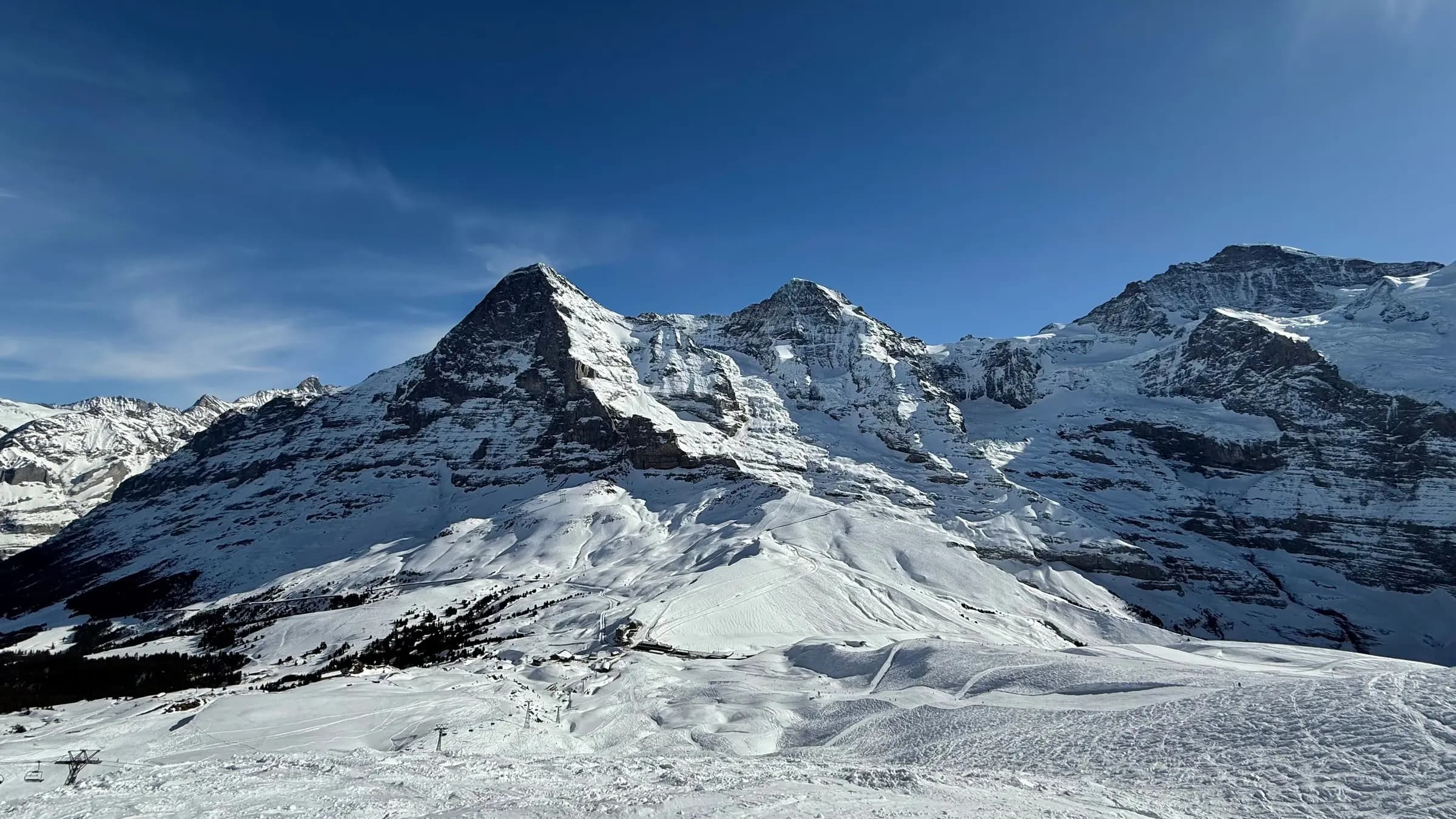 Breathtaking view of snow-covered peaks in Grindelwald, Switzerland, under a clear blue sky.
