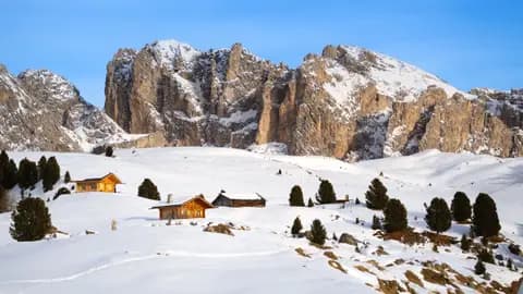 Charming rustic huts amidst snow-covered landscape in the Italian Alps.