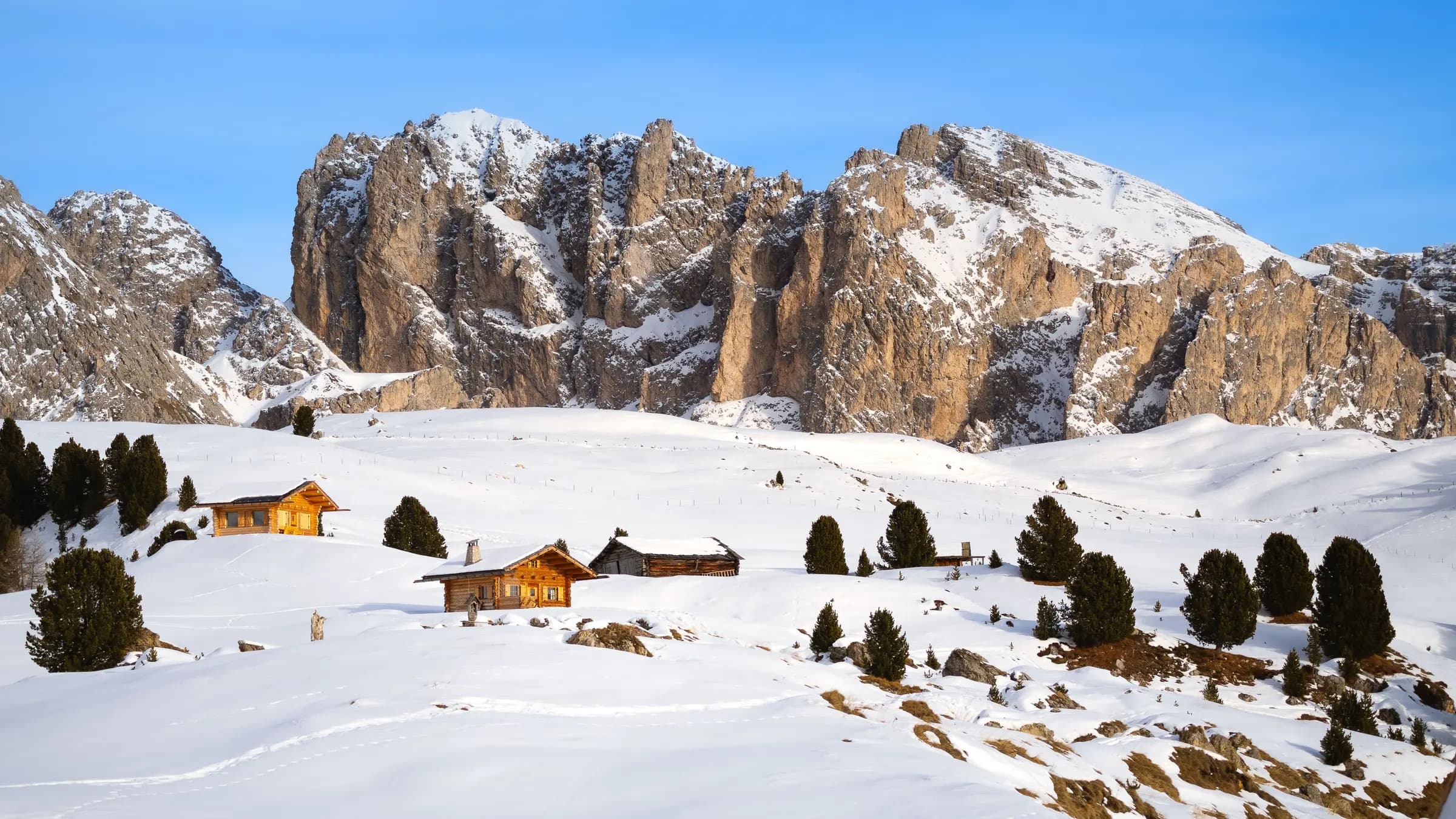 Charming rustic huts amidst snow-covered landscape in the Italian Alps.
