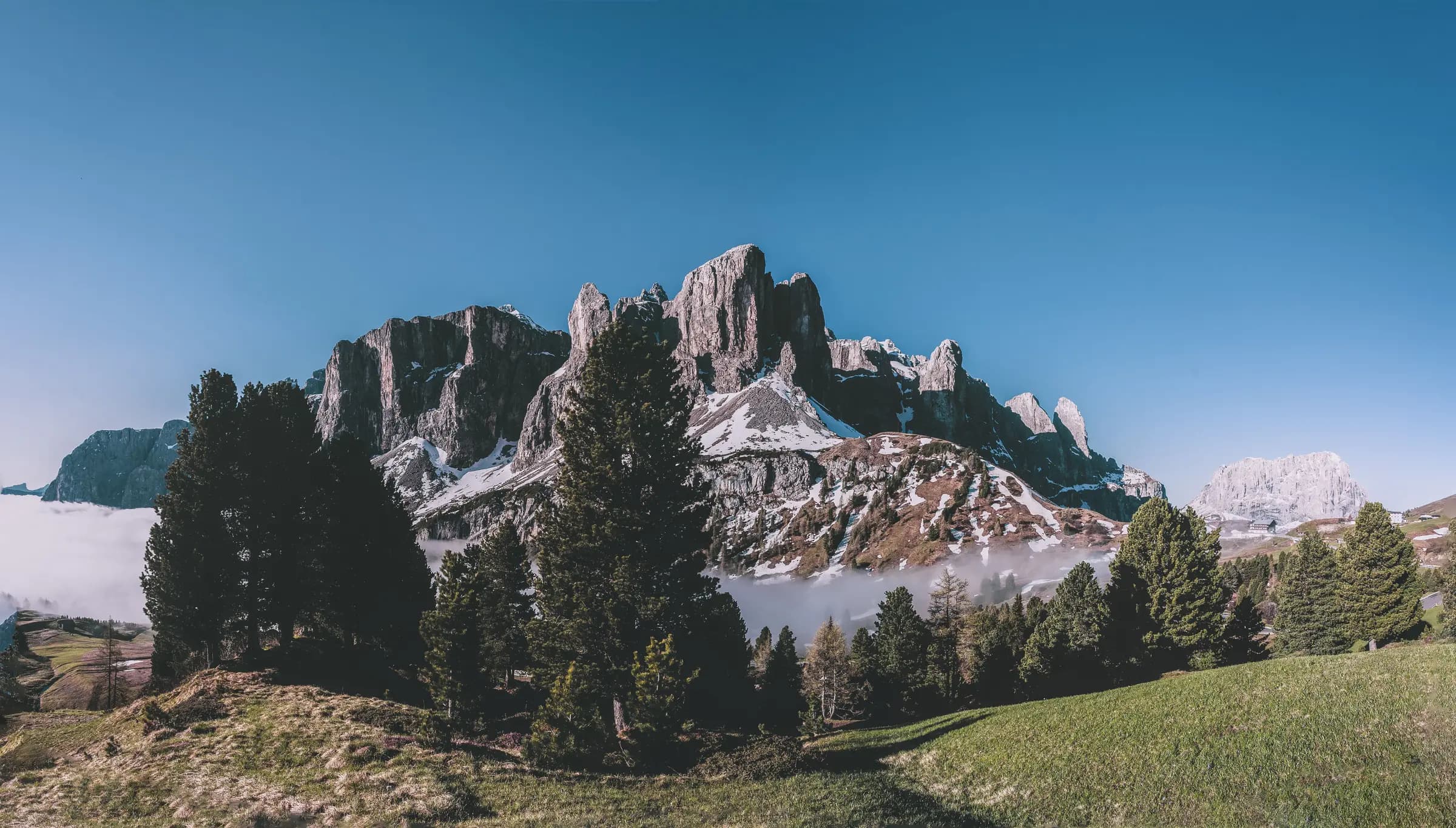 Majestic view of the Dolomites in Selva di Val Gardena, Italy, with clear skies and lush greenery.