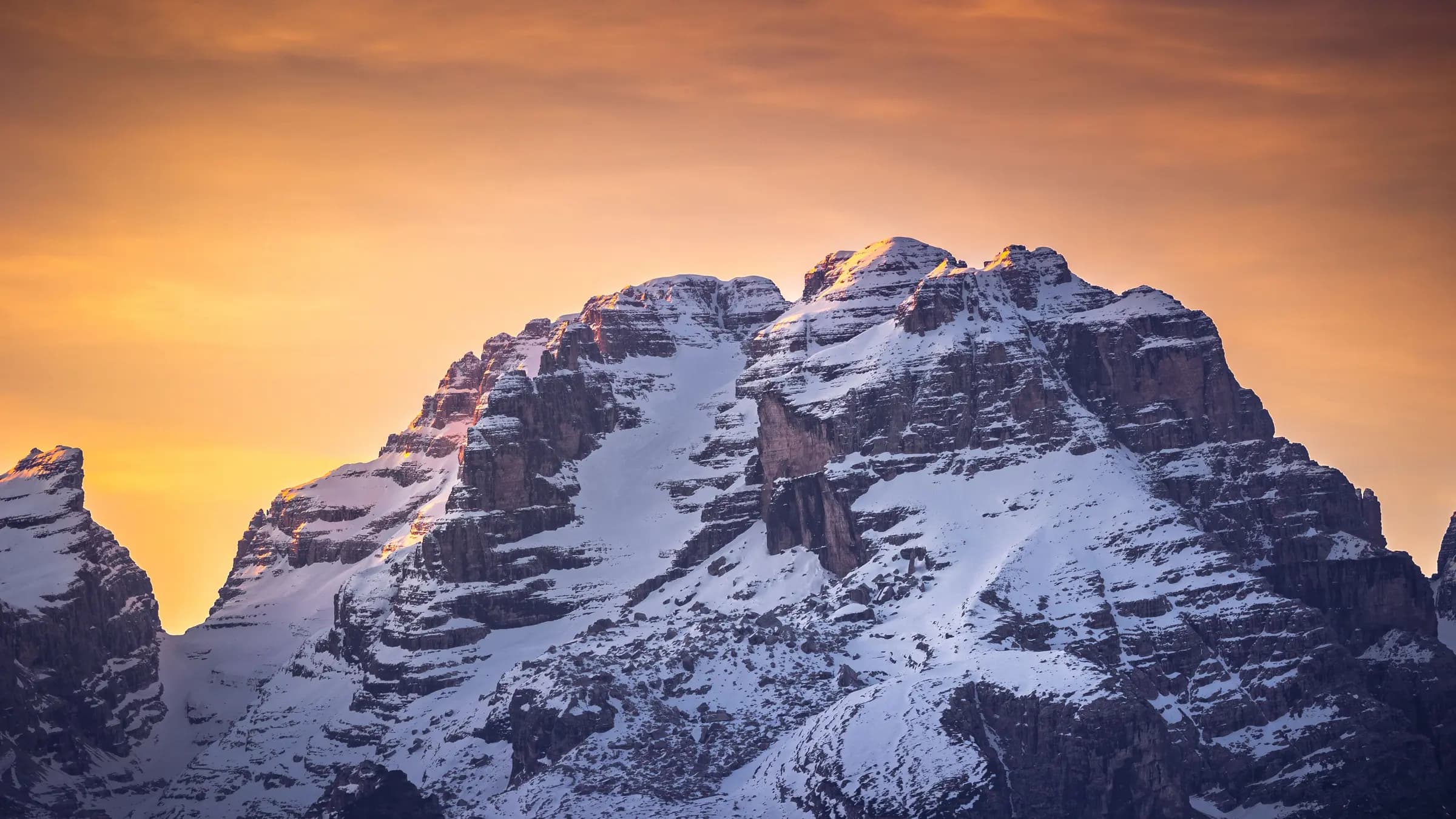 Breathtaking view of snow-covered mountains at sunset in Madonna di Campiglio, Italy.