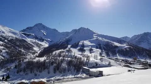 Mount Sises (to the right) and Mount Rognosa (to the left) as viewed from the lower slopes of Mount Fraiteve. The town of Sestriere, Italy is in the foreground to the right of the image. Mount Sises hosts a major portion of the Sestriere ski resort within the larger Via Lattea ski area.