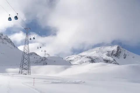 Beautiful snowy mountain landscape with blue cable cars in winter.