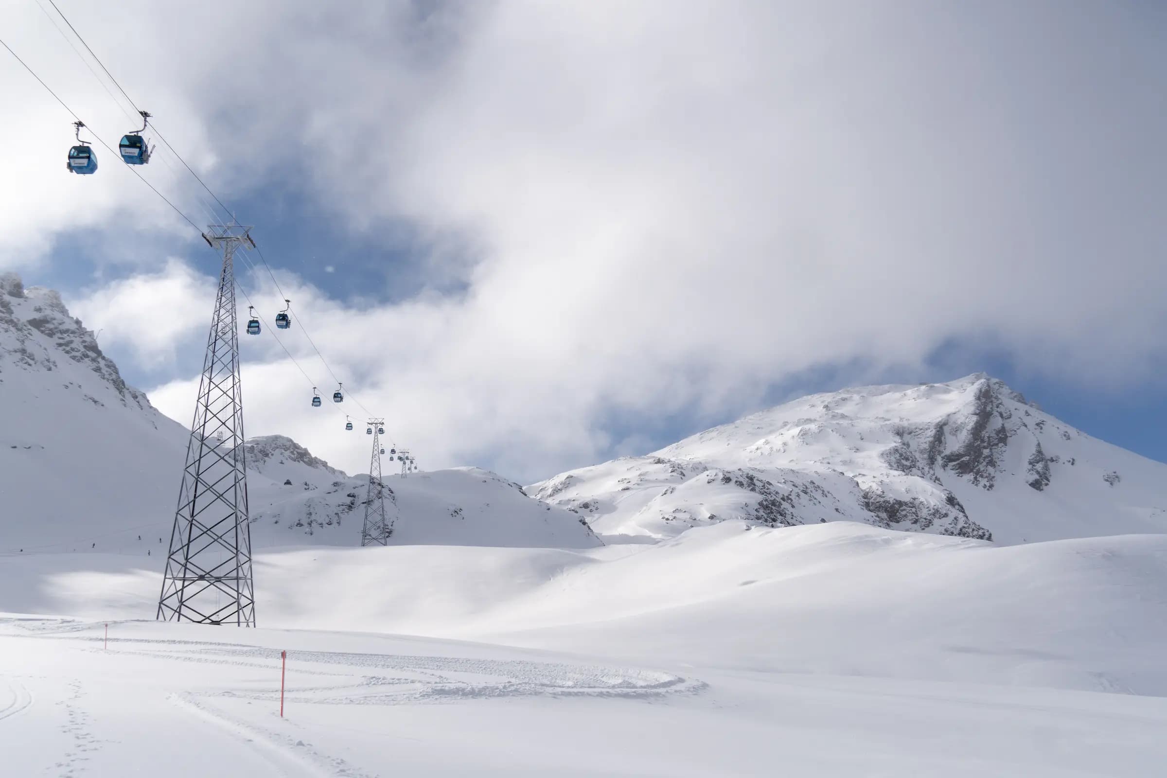 Beautiful snowy mountain landscape with blue cable cars in winter.