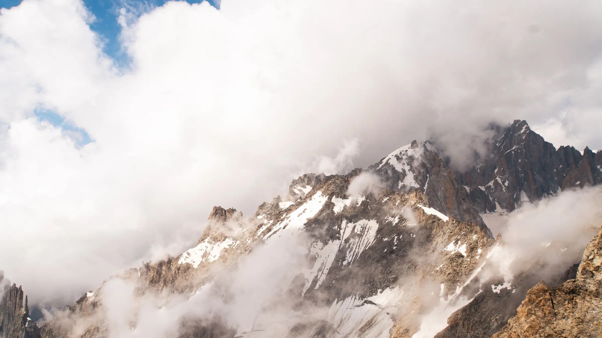 Breathtaking view of Mont Blanc peaks in Courmayeur, Italy, covered with clouds and snow.
