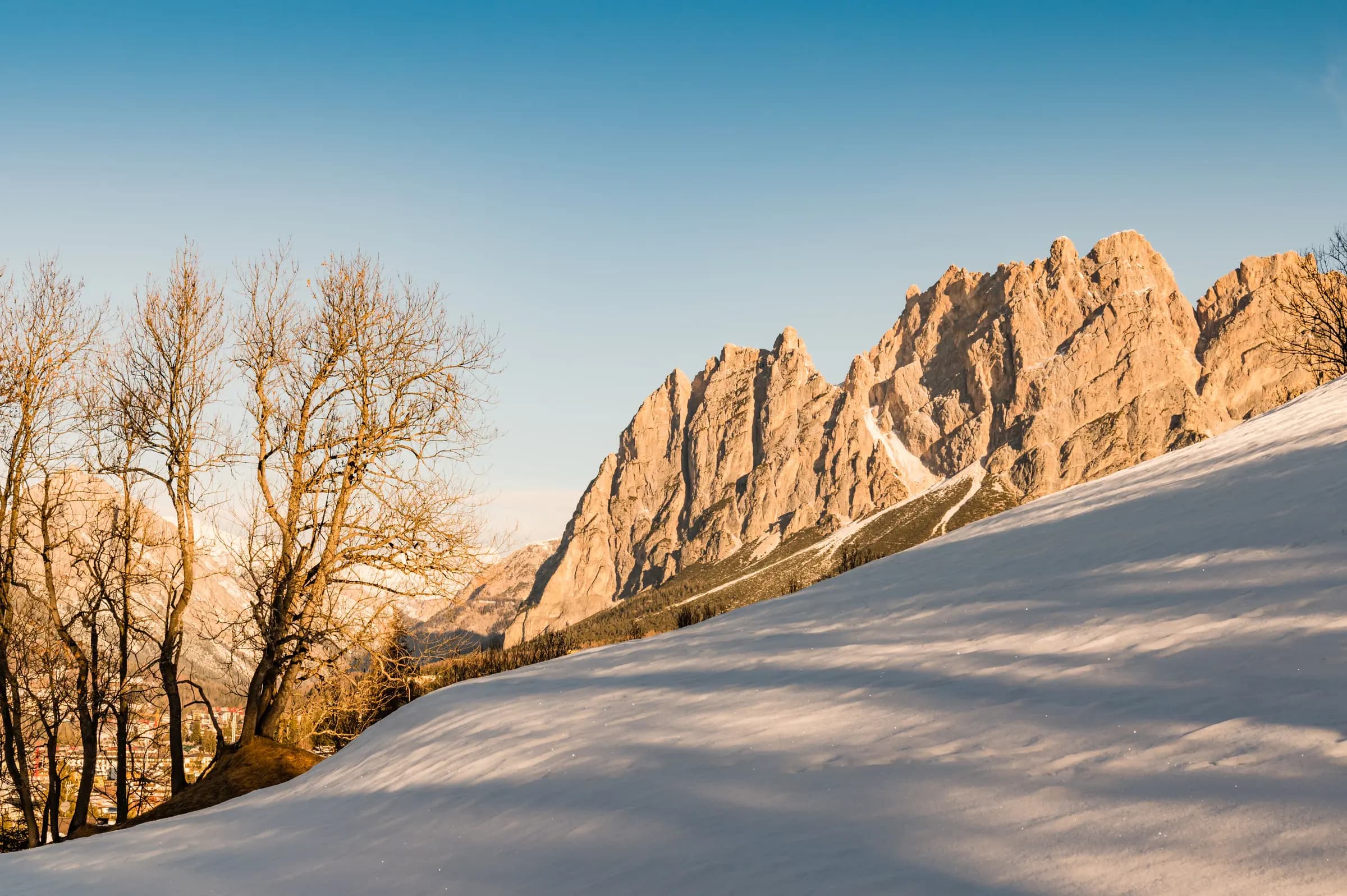 Beautiful snowy landscape of the Dolomites in Cortina d'Ampezzo, Italy, showcasing bare trees and rocky peaks.