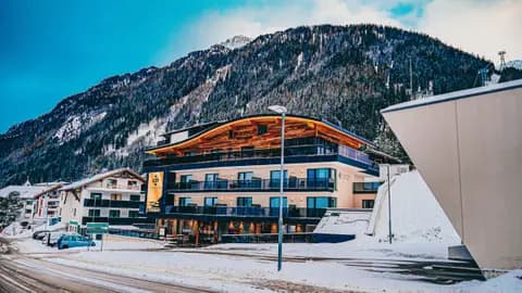 Empty road in front of modern ski resort cottage near snowy mountains on sunny winter day