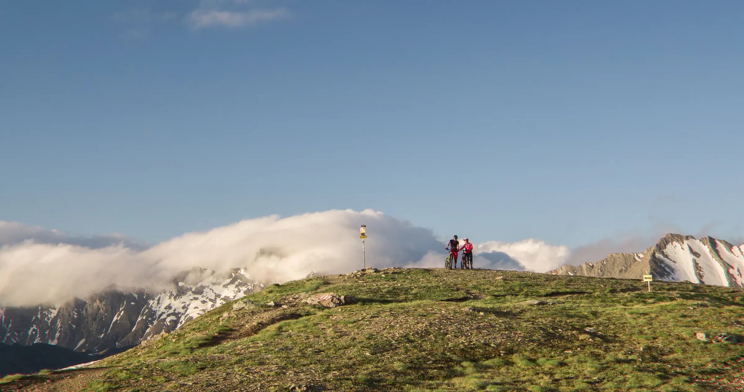 Couple cycling atop a mountain in Ischgl, Austria, with breathtaking views of the Alps.
