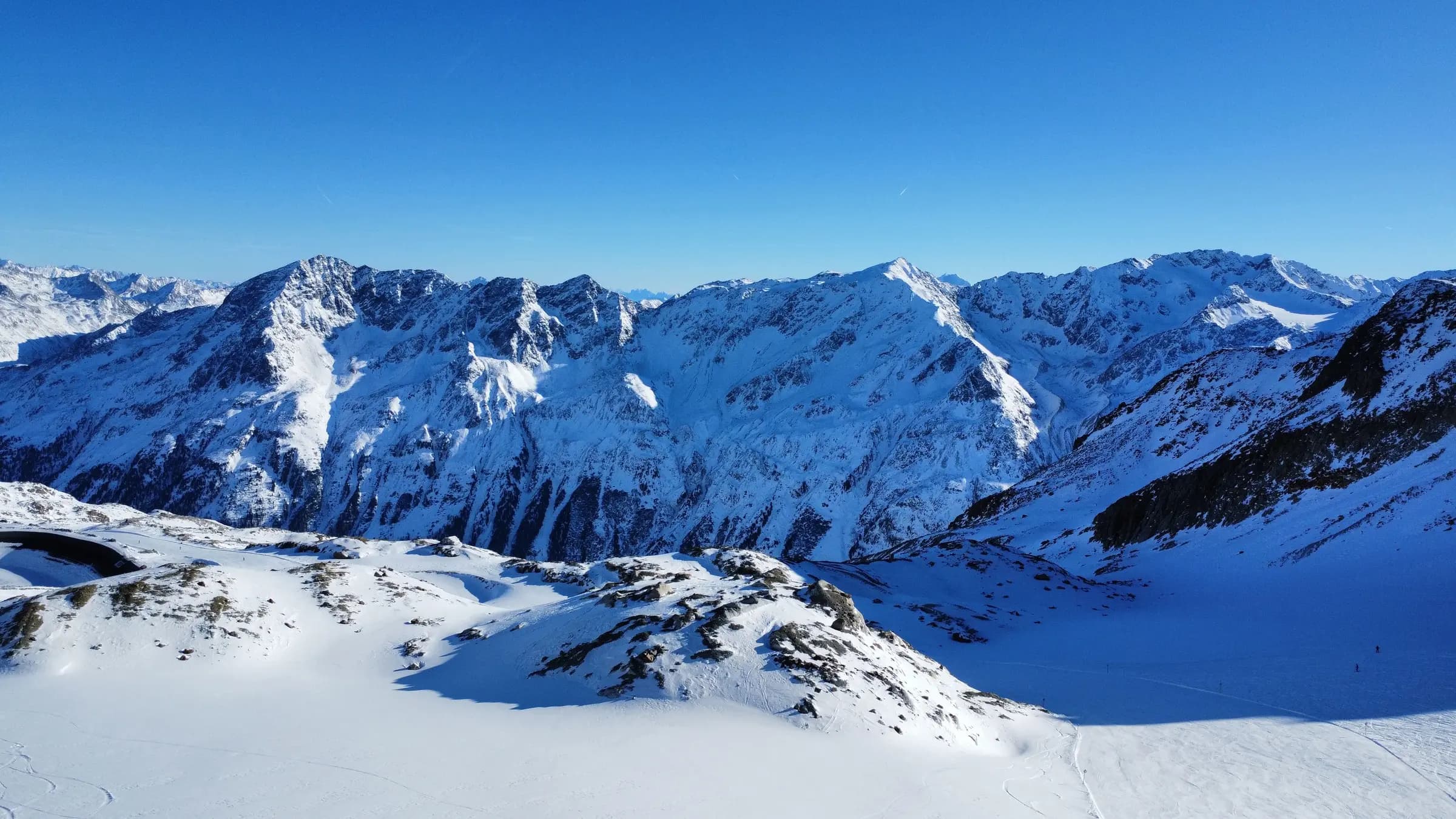 Spectacular view of snow-covered Alps under a clear blue sky, capturing winter serenity.