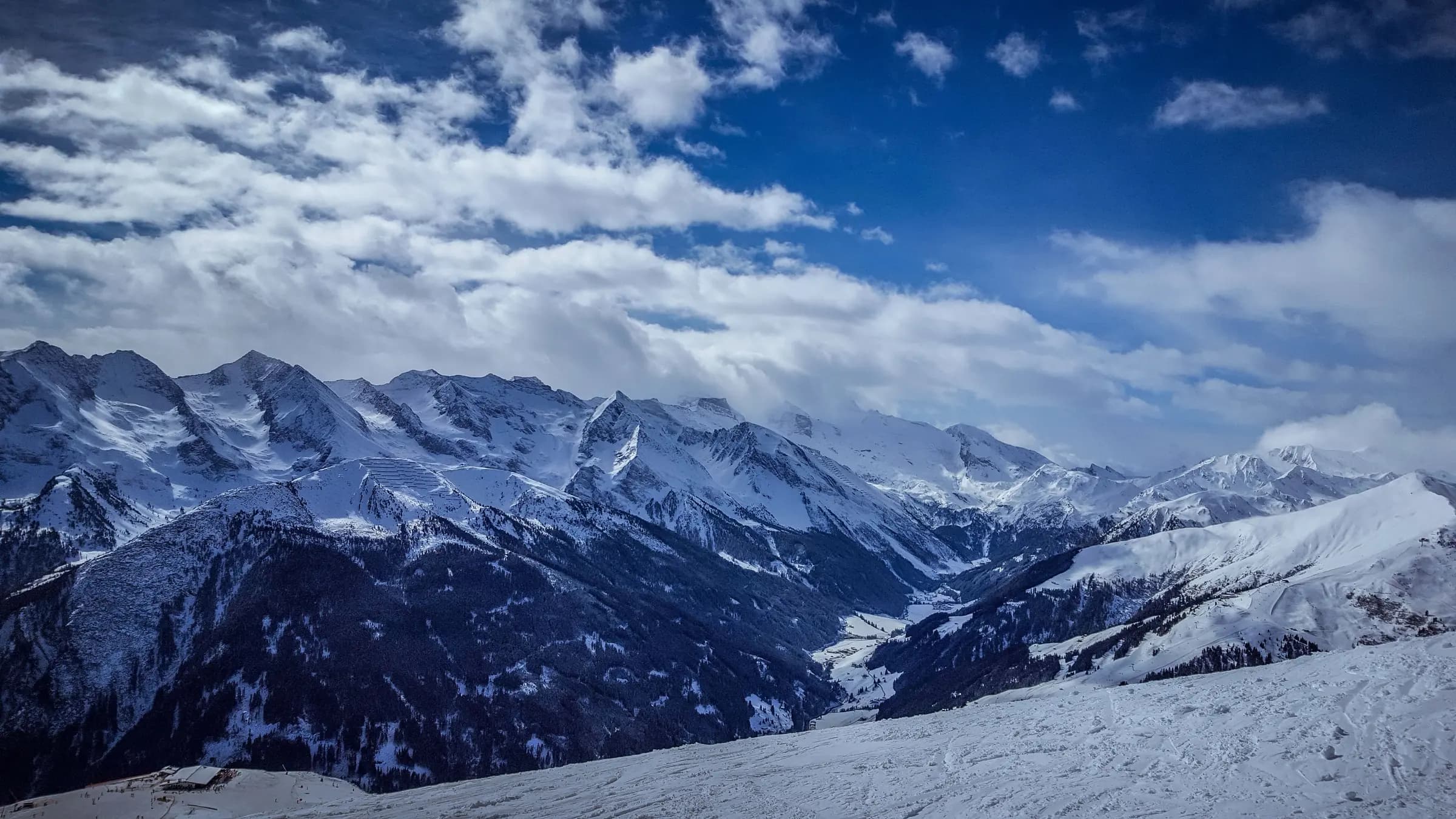 Panoramic view of snow-covered alpine mountains under a cloudy sky in Mayrhofen, Austria.