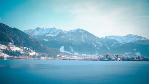 A breathtaking winter view of snow-capped Alps and serene Lake Zell in Zell am See, Austria.
