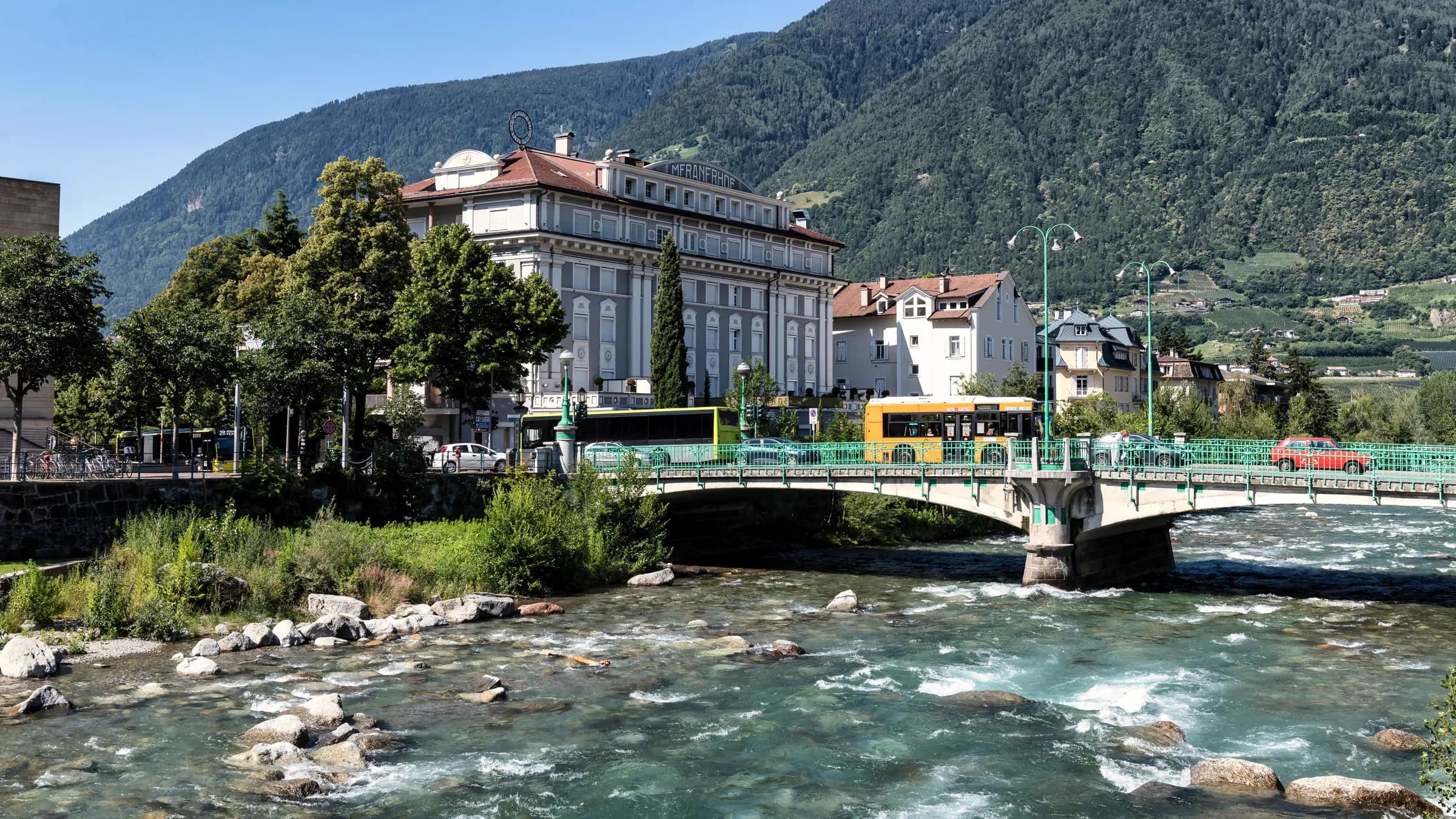 Idyllic riverfront in Merano showcasing historic architecture and scenic mountain backdrop.