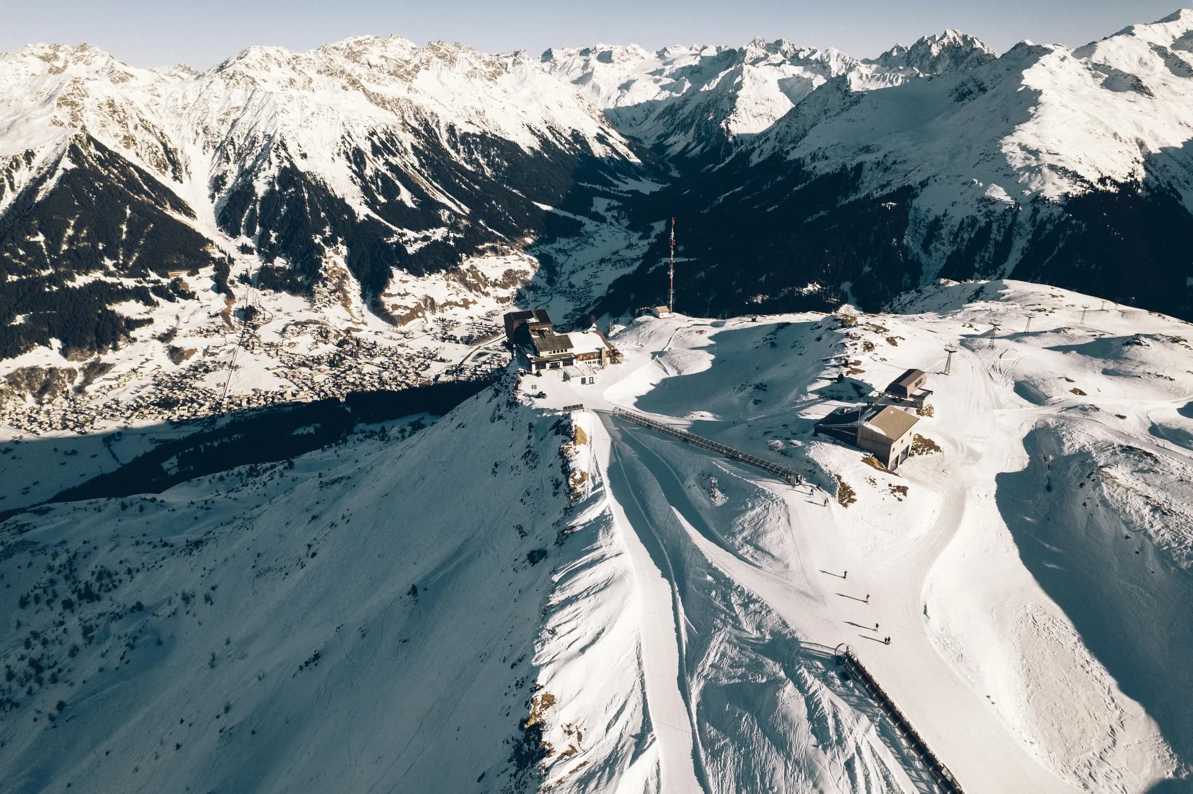 Breathtaking aerial view of a snow-covered ski resort in Klosters-Serneus, Switzerland, surrounded by the majestic Alps.