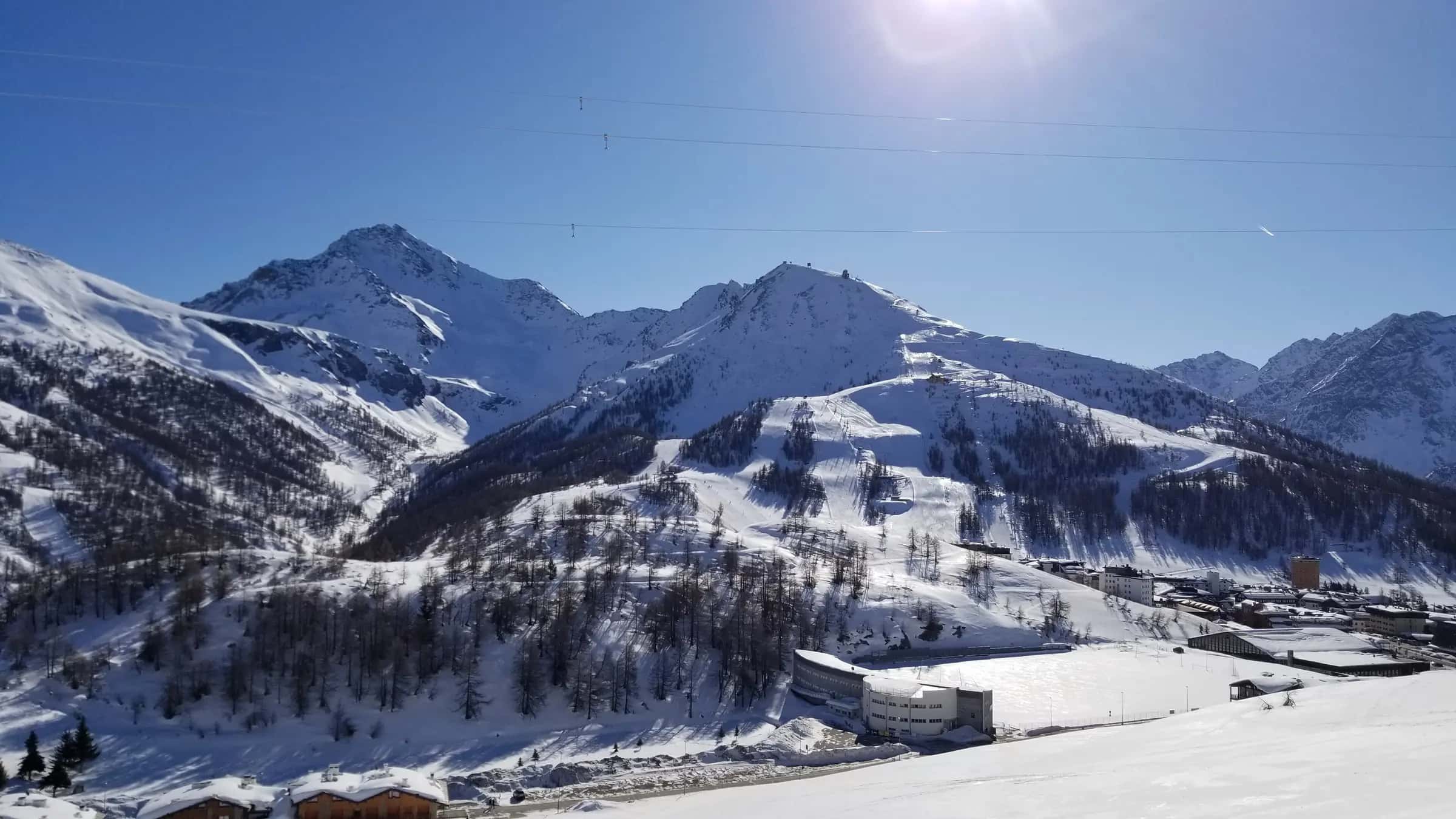 Mount Sises (to the right) and Mount Rognosa (to the left) as viewed from the lower slopes of Mount Fraiteve. The town of Sestriere, Italy is in the foreground to the right of the image. Mount Sises hosts a major portion of the Sestriere ski resort within the larger Via Lattea ski area.