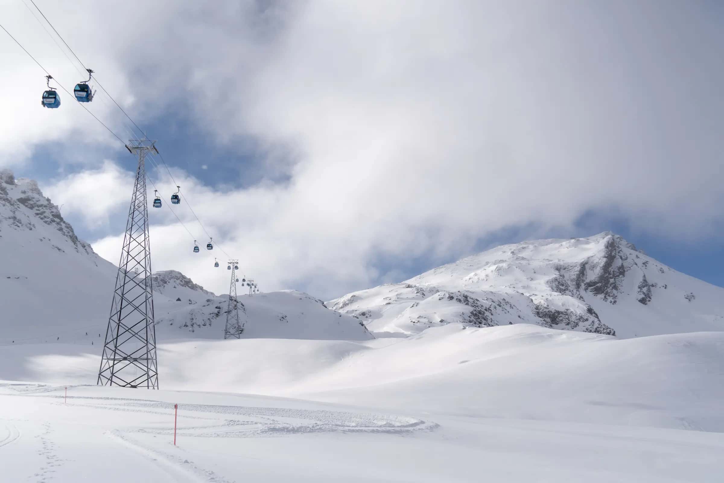 Beautiful snowy mountain landscape with blue cable cars in winter.